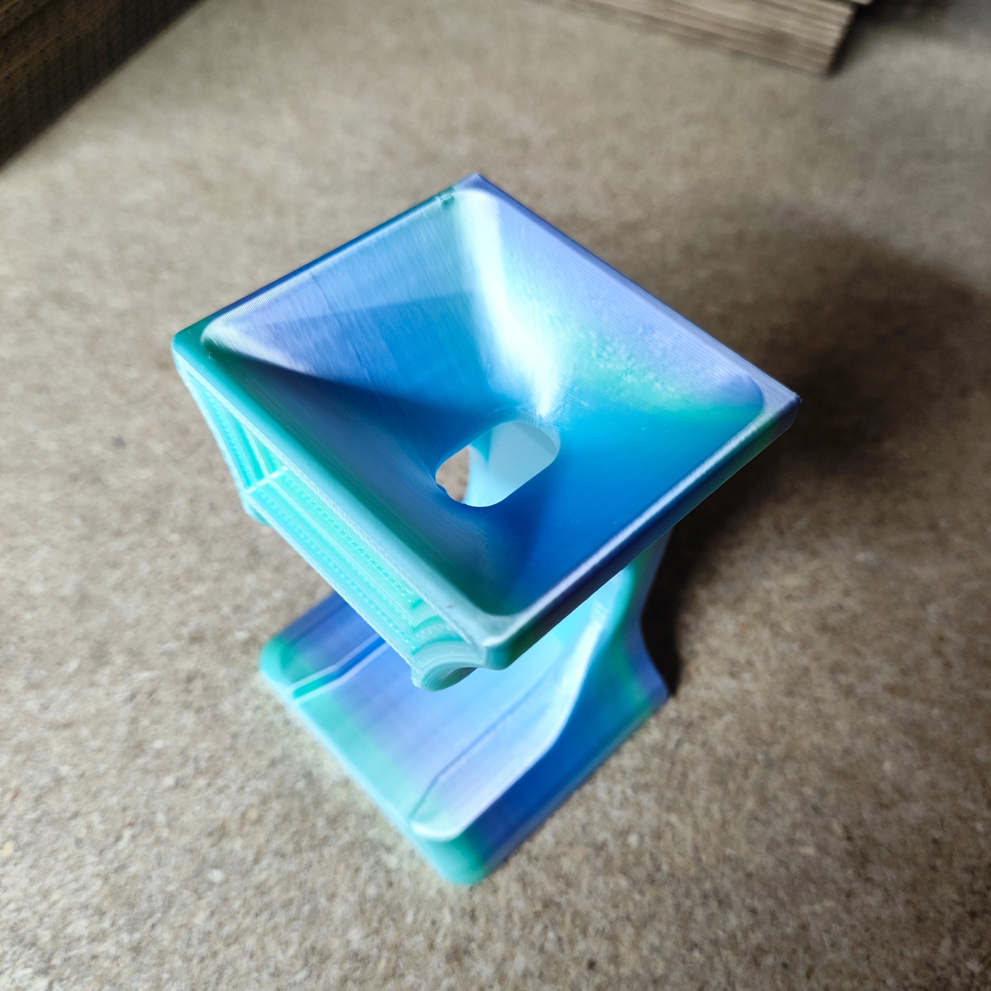 Der Diamond Painting Trichter für runde Dosen von New Plastics ist ein 3D-gedrucktes, mehrfarbiges Objekt mit einer trichterförmigen Oberseite zum sauberen Befüllen und einem abstrakten, geschwungenen Körper. Er verfügt über eine glatte, glänzende Oberfläche und ruht auf einer flachen Basis, die sich ideal für runde Dosen eignet.