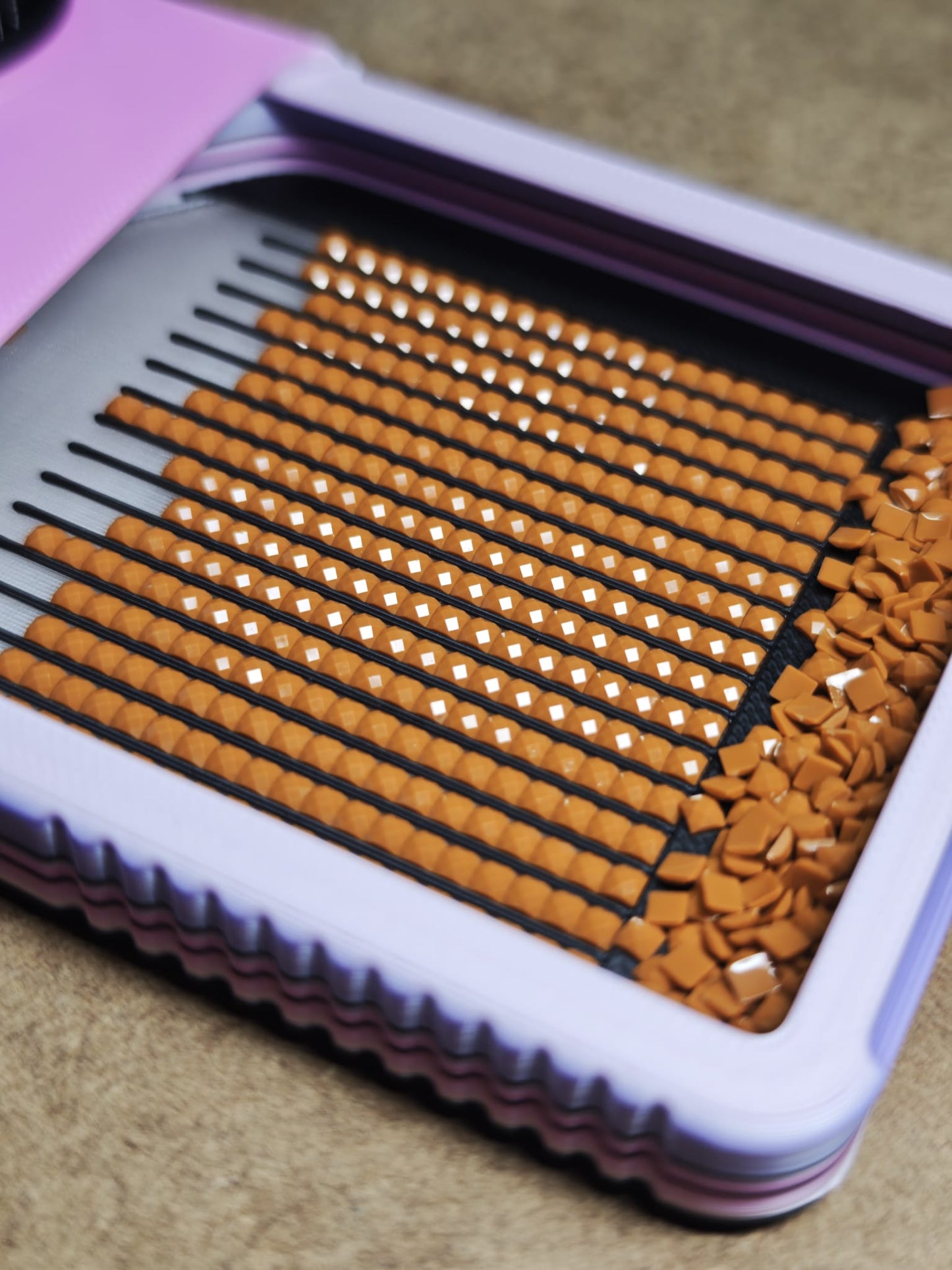 Eine Nahaufnahme des New Plastics Diamond Painting Schiffchen S4, einem Plastikbehälter, in dem sich ordentlich Reihen brauner Wimpernverlängerungen mit weißen Spitzen befinden, die an Diamond Painting-Edelsteine erinnern, sowie zusätzliche einzelne Verlängerungen an der Seite.