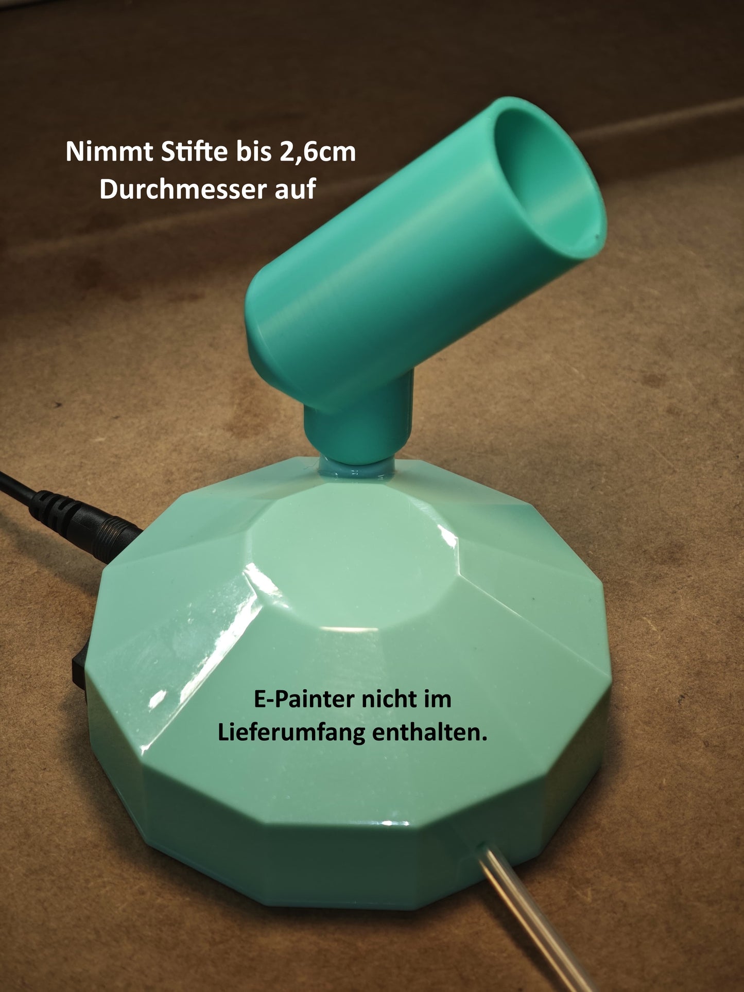 Ein türkiser New Plastics Stifthalter für Ideen mit Herz E-Painter mit runder Basis und abgewinkeltem Rohr auf brauner Oberfläche; Passend für ergonomische Stiftmodelle bis 2,6cm Durchmesser. E-Painter nicht enthalten.