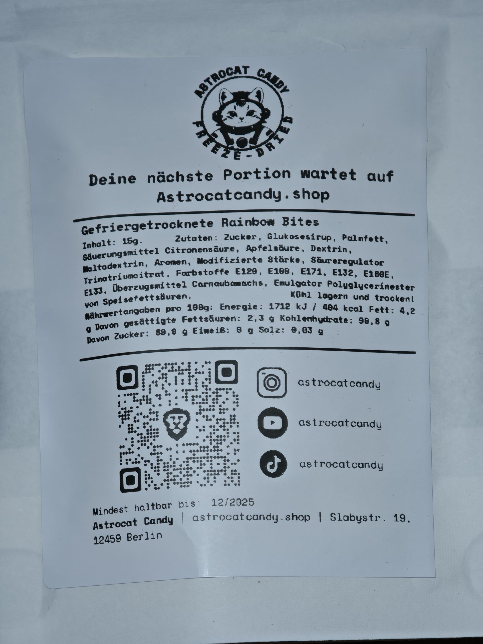 Die 15-g-Packung der Astrocat Candy Rainbow Bites enthält ein Katzen-Astronauten-Logo, einen deutschen Text zu veganen Zutaten, den Fruchtgeschmack und die gefriergetrockneten Rainbow Bites. Nährwertangaben, QR-Code, Social-Media-Symbole, Gewichtsangaben und das Verfallsdatum sind ebenfalls enthalten.