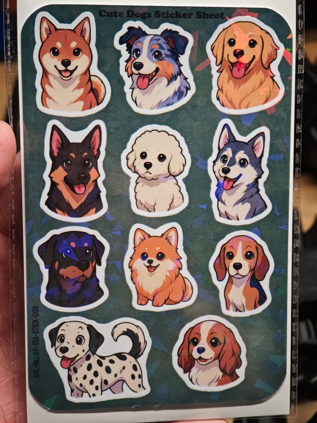 Der New Plastics Cute Dogs Stickerbogen (ca. DIN A6) enthält 11 bunte Vinyl-Aufkleber verschiedener Hunderassen – perfekt für DIY-Projekte oder zum Personalisieren Ihrer Lieblingsgegenstände.