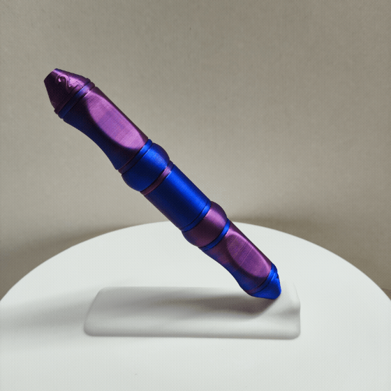 Der Modularer Diamond Painting Stift von New Plastics ist ein metallischer, zweifarbiger Stift mit violettem und blauem Farbverlauf, der Rillen und spitze Enden für Präzision aufweist. Auf einem weißen Ständer vor neutralem Hintergrund präsentiert, ist er ideal für Diamond Painting-Enthusiasten.